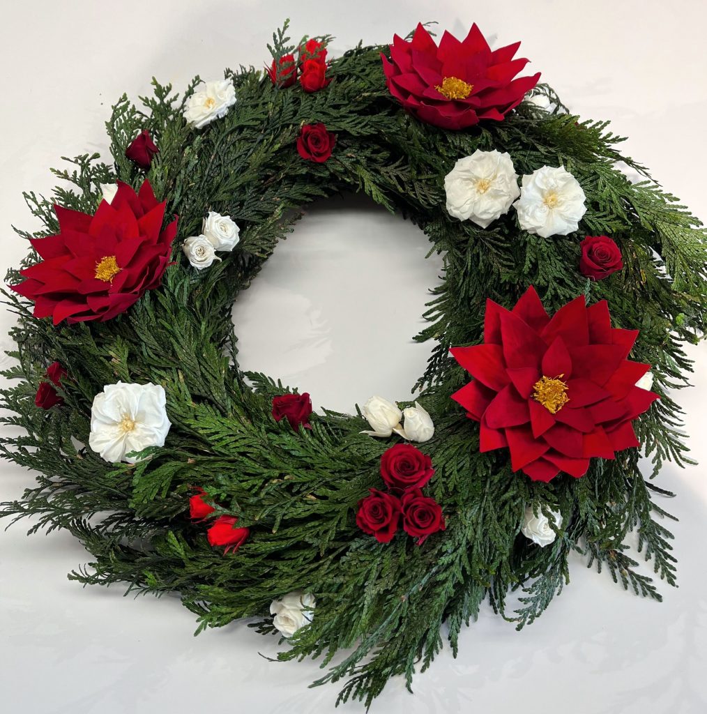 webinar couronne de noel stabilisées avec des poinsettias, des gardenias et des roses de petites tailles rouges et blanches sur une base de thuja. stabilised christmas wreath with poinsettias, gardenias and small red and white roses on a thuja base.