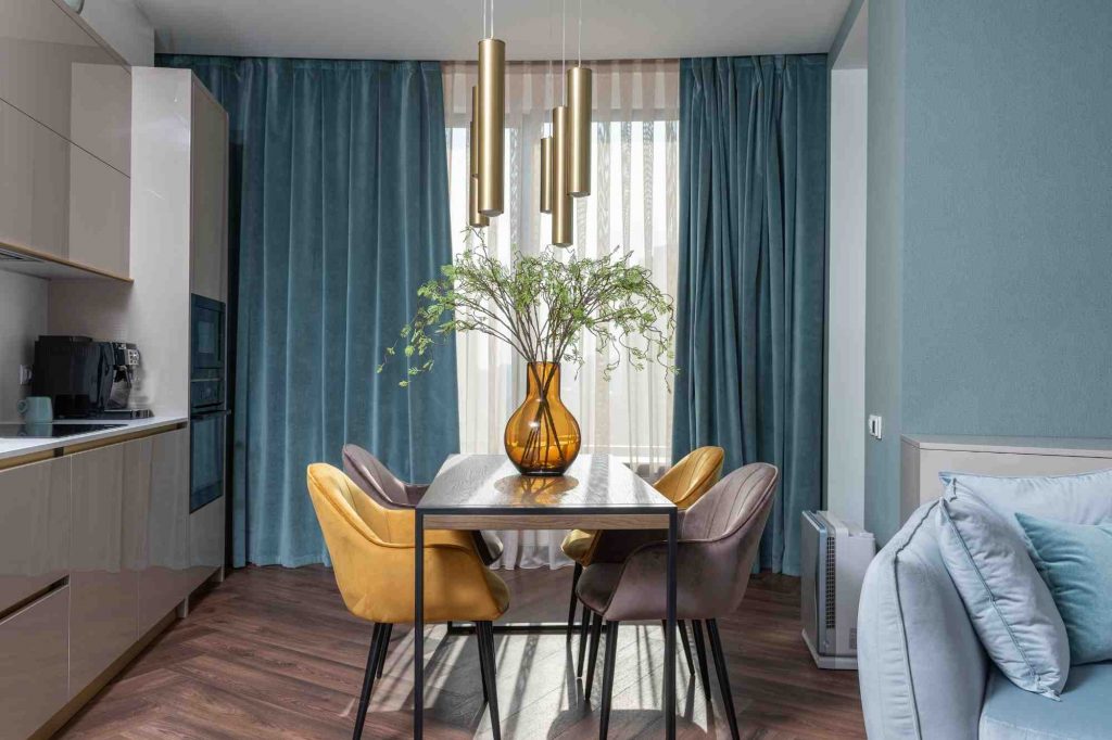 living-dining room with brown kitchen and subtle modern blue on the walls and curtains salon salle à manger avec cuisine marron et bleu subtil moderne sur les murs et les rideaux