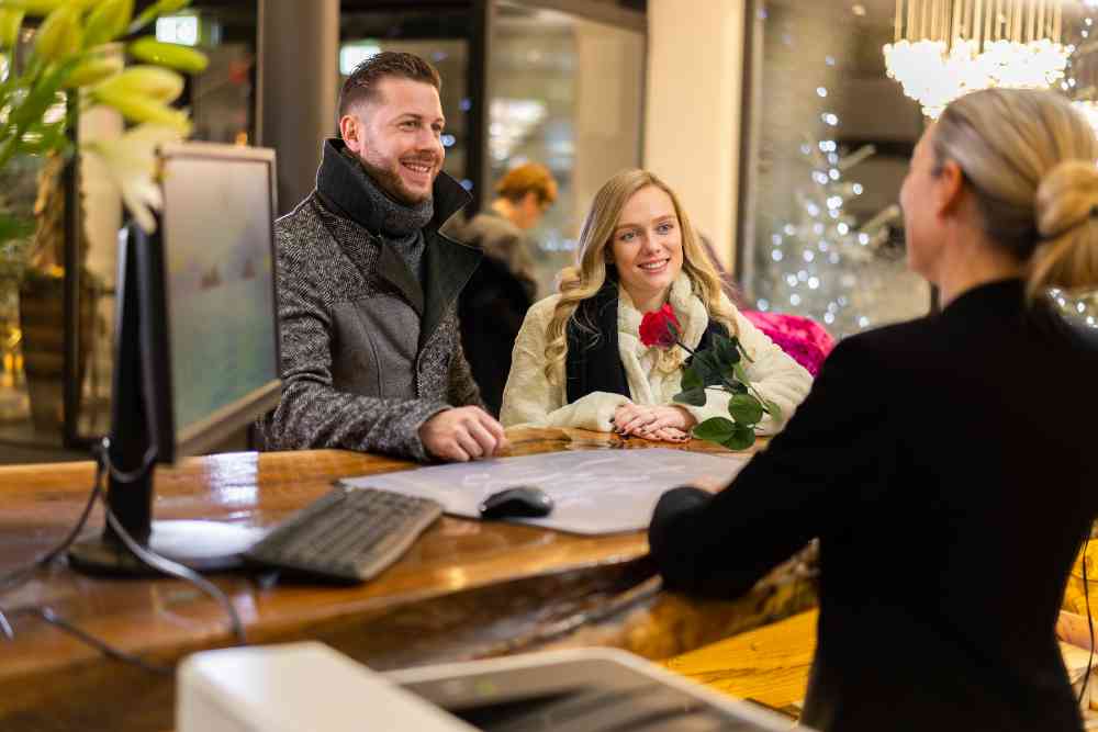 A receptionist gives a red rose to a loving couple in a hotel lobby for Valentine's Day Une réceptionniste offre une rose rouge à un couple d'amoureux dans le hall d'un hôtel pour la Saint-Valentin.